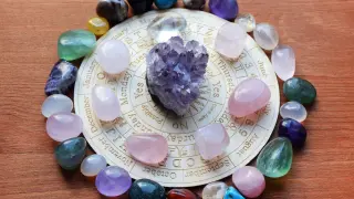Kryształowa kula i kolorowe kamienie znaki zodiaku tworzą magiczny krąg na drewnianym tle.