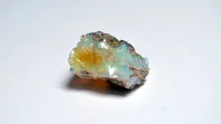 Surowy opal, opalit, mieni się odcieniami zieleni, błękitu i żółci, ukazując swoje magiczne piękno.